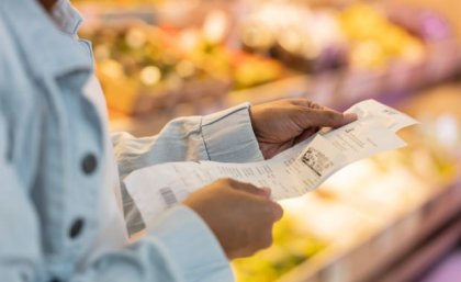 Woman looking at receipts in supermarket. Image, Adobe